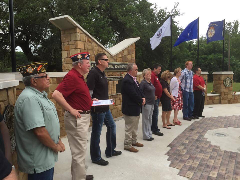 Officials, veterans stand in front of monument