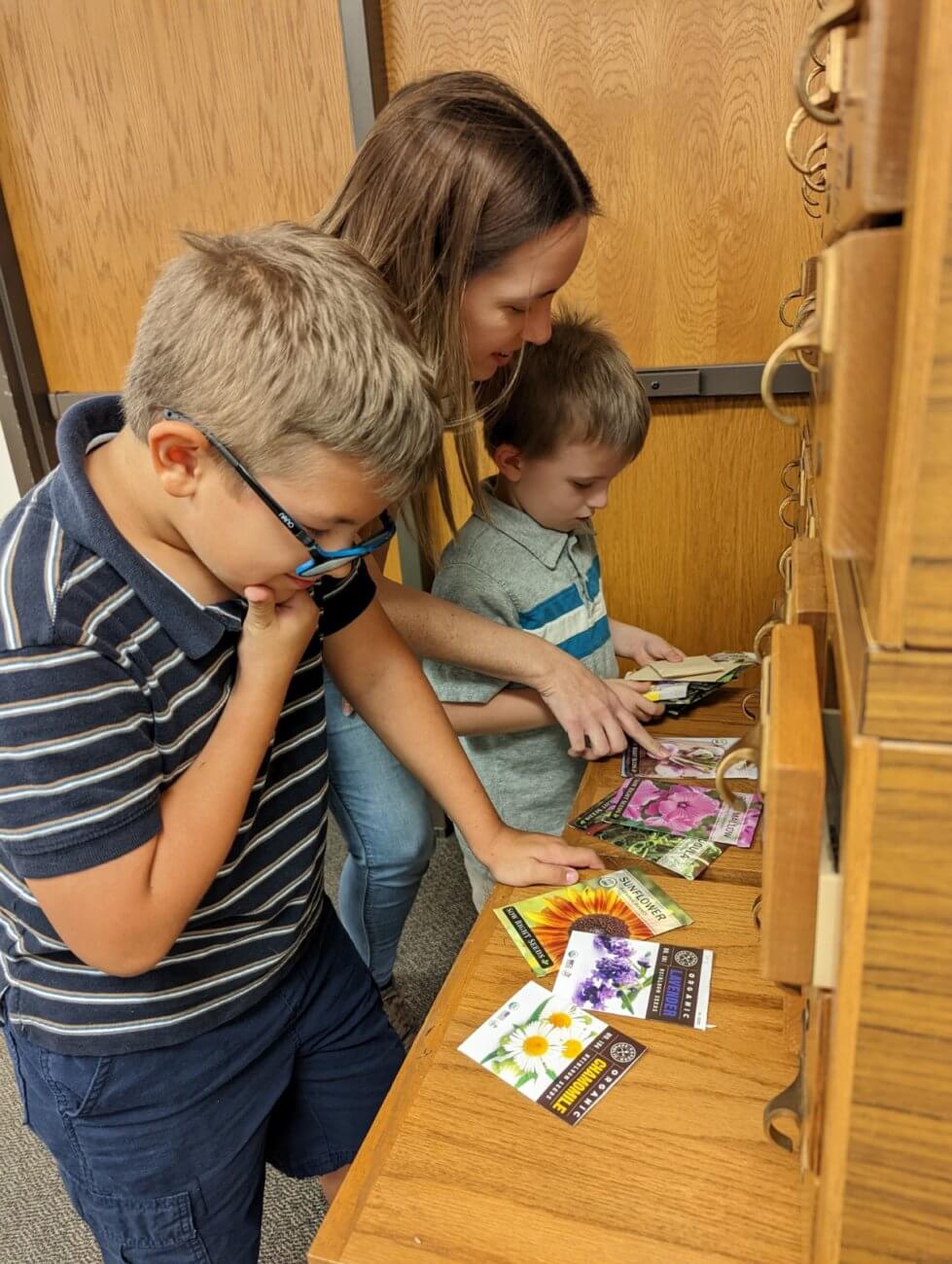 Mother and sons enjoy looking through Seed Library packets together.