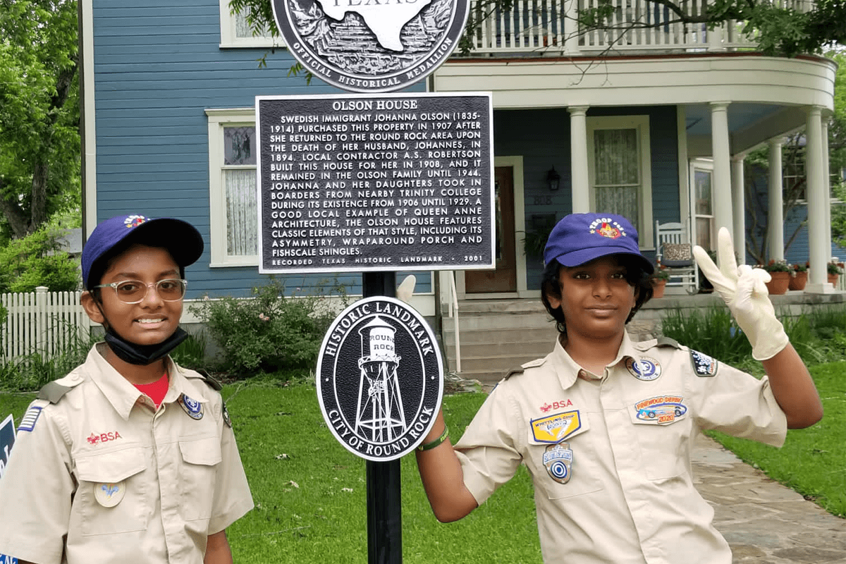 Two Boy Scouts smile after cleaning a historic marker