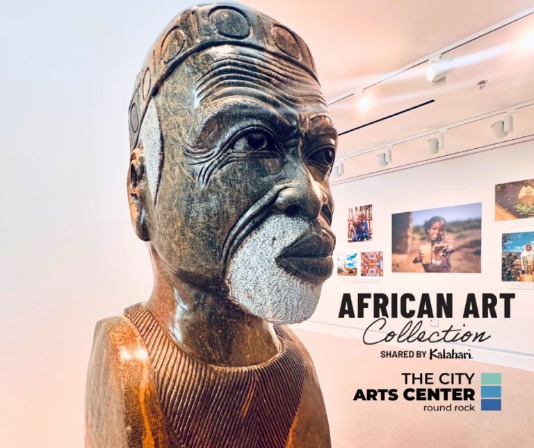 Close-up of a carved wooden African bust in a bright art gallery near me. Photographs line the walls in the background. Text reads: African Art Collection, Shared by Kalahari, and The City Arts Center Round Rock.