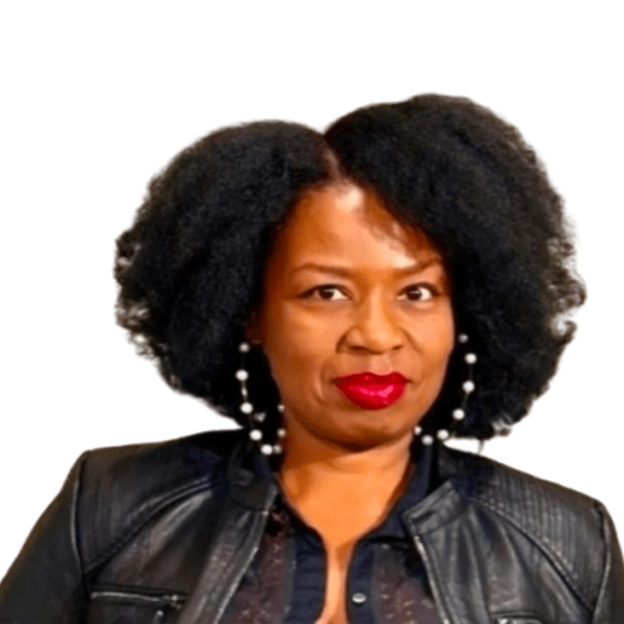 A woman with natural curly hair, wearing a black leather jacket, a sheer black top, and pearl earrings, poses against a white background.