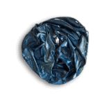 A crumpled, glossy, dark blue and green material forms an irregular circular shape against a plain white background.