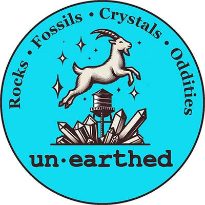 A circular logo with a goat leaping over a water tower and large crystals, surrounded by the words: Rocks, Fossils, Crystals, Oddities. The brand name un•earthed is at the bottom on a bright blue background—perfect for a summer reading program.