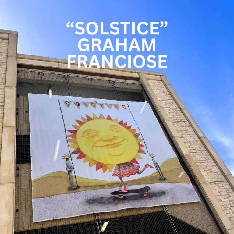 A large mural titled Solstice by Graham Franciose hangs on a building, featuring a smiling sun with a face, wearing red shoes and balancing on a skateboard under a blue sky.
