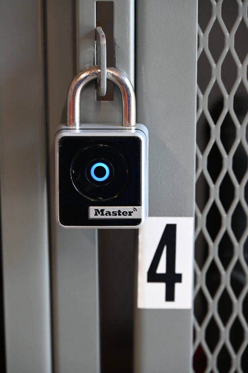 A Master brand smart padlock with a circular blue light is attached to a gray metal locker door labeled with the number 4.