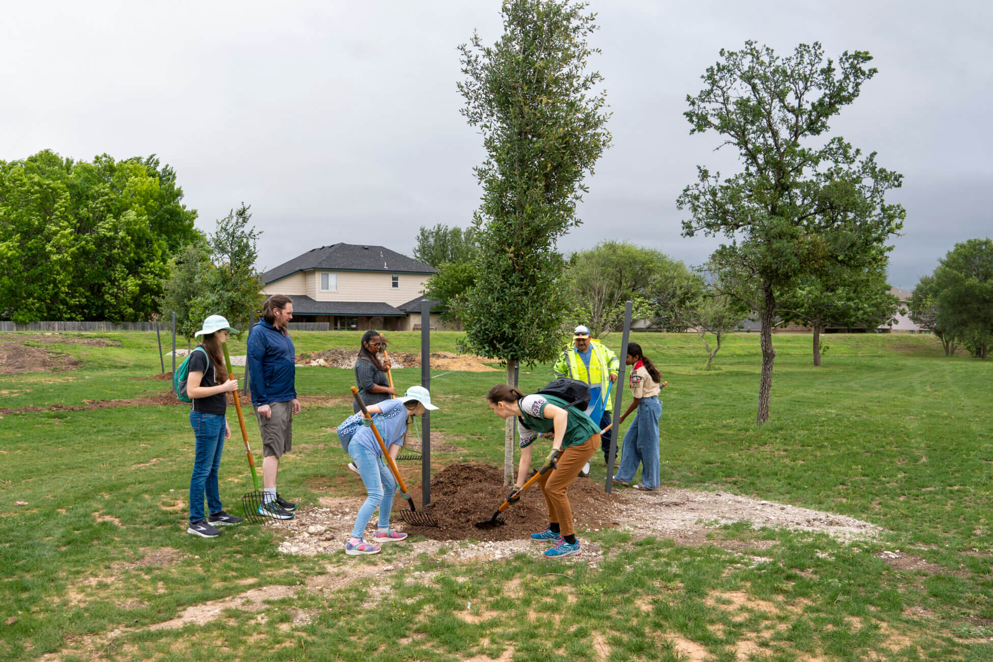 People work together to mulch and support a newly planted tree during an Earth Day 2026 activity in Round Rock.