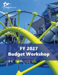 Bright playground equipment in yellow and gray with slides and climbing structures, set against a blue sky. Text overlay reads FY 2027 Budget Workshop with the Round Rock, Texas logo in the top left corner.