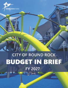 Cover of City of Round Rock Budget in Brief FY 2027 featuring a modern playground with bright yellow climbing equipment and blue flooring.
