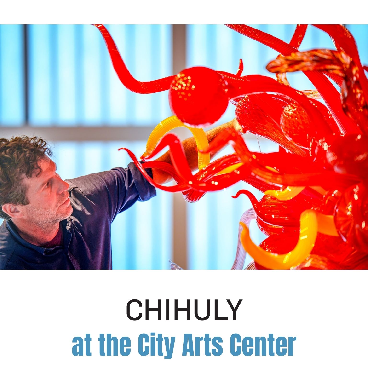 A man examines a vibrant red and yellow glass sculpture with twisting shapes. Text reads: CHIHULY at the City Arts Center..