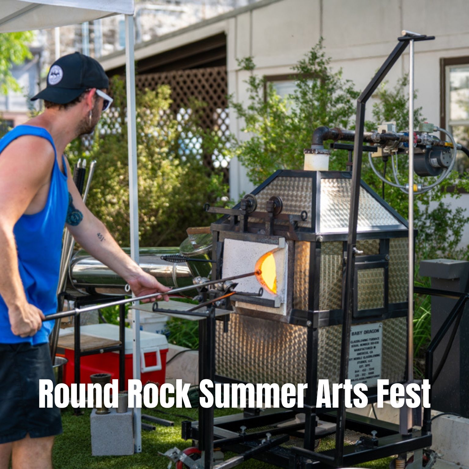 A person in a blue tank top shapes molten glass using a rod and furnace at an outdoor event. Text on the image reads, Round Rock Summer Arts Fest..