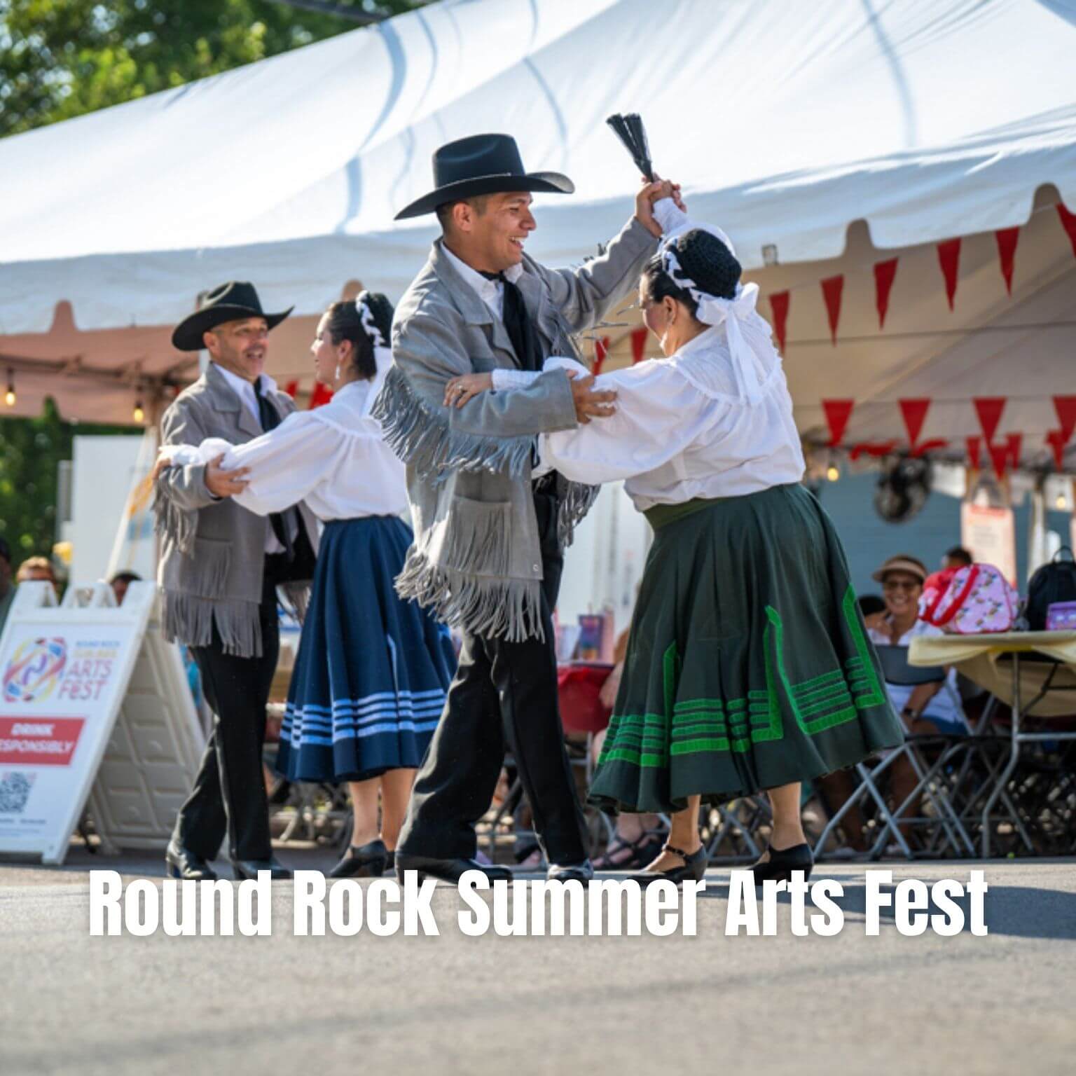 Four dancers in traditional attire perform outside near a white tent at the Round Rock Summer Arts Fest. People watch from tables in the background.