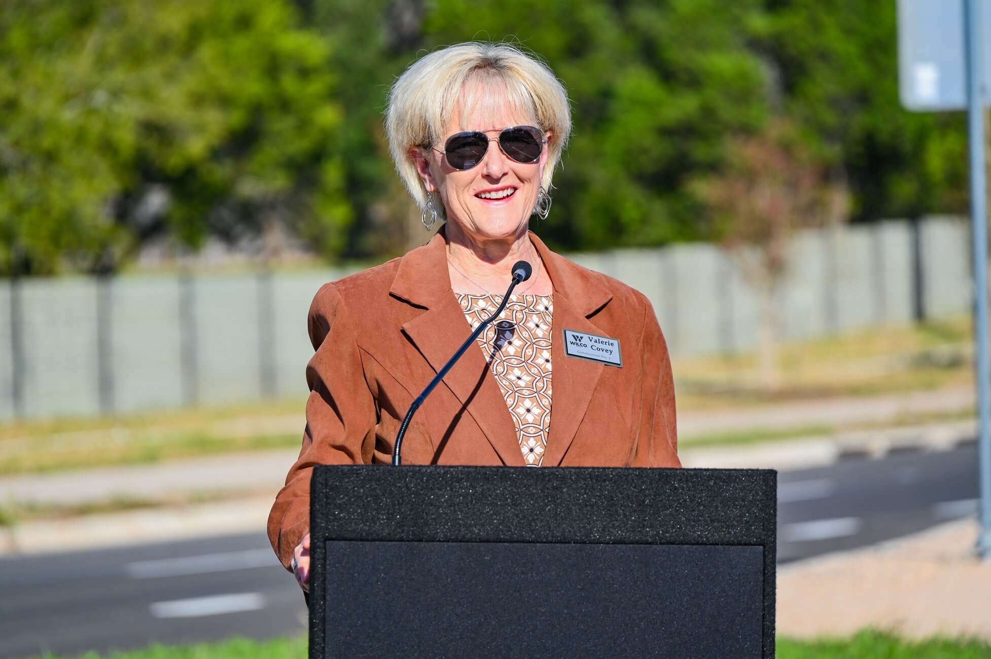 Valerie Covey speaking at a podium outdoors.